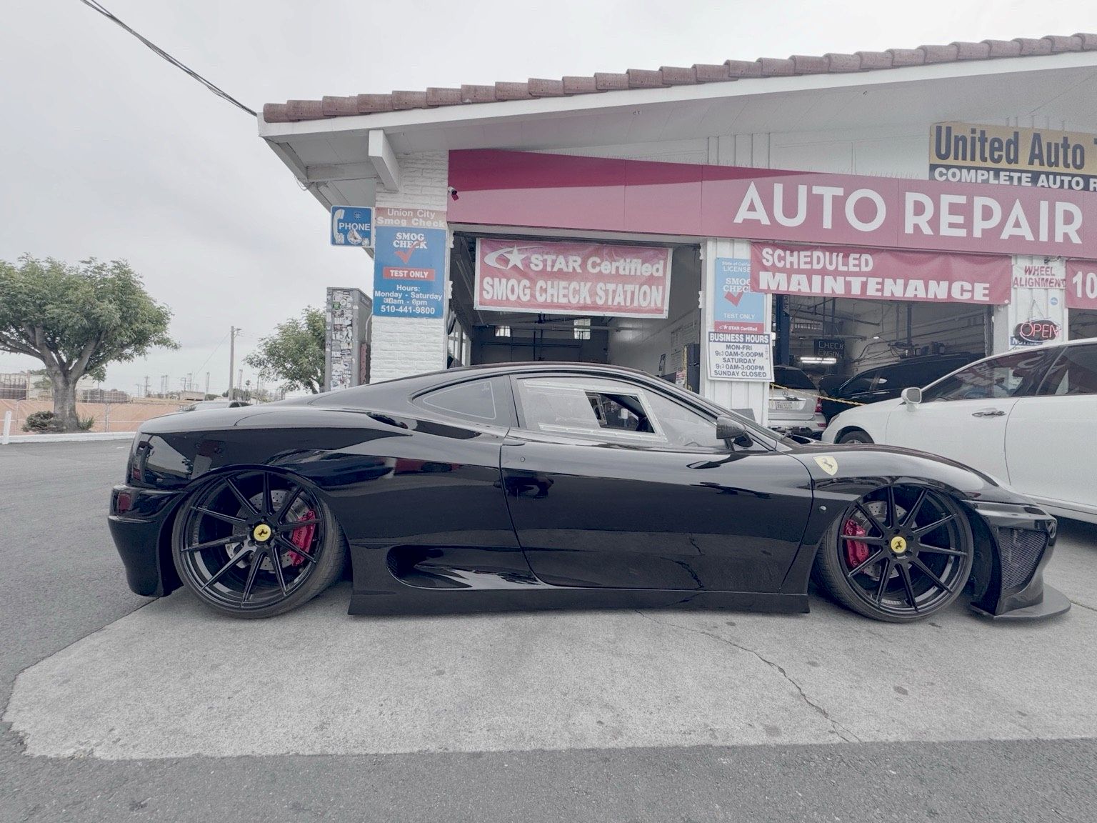 Black Ferrari 360 in front of the Union City Smog Check building, with the blue Smog Check sign and STAR Certified banner