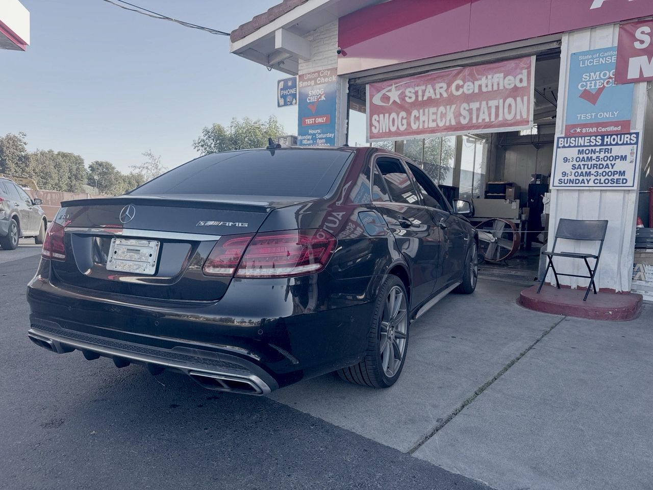 Black Mercedes-Benz E63 AMG at the Union City Smog Check bay, under the STAR Certified Smog Check Station banner